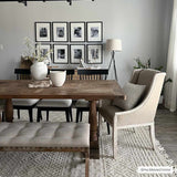 Farmhouse dining room with a wood table, tufted bench, and the Ryne Area Rug in driftwood and white thatch. Roomscene-Rectangle