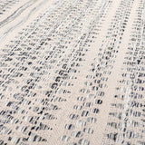 Close-up of the hand woven Arabi Wool Area Rug. Black, gray, and light beige create a textured, transitional design. Texture