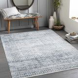 Entryway with blue and gray Askeaton Washable Area Rug, wood bench, round mirror, and gray walls. Roomscene-Rectangle