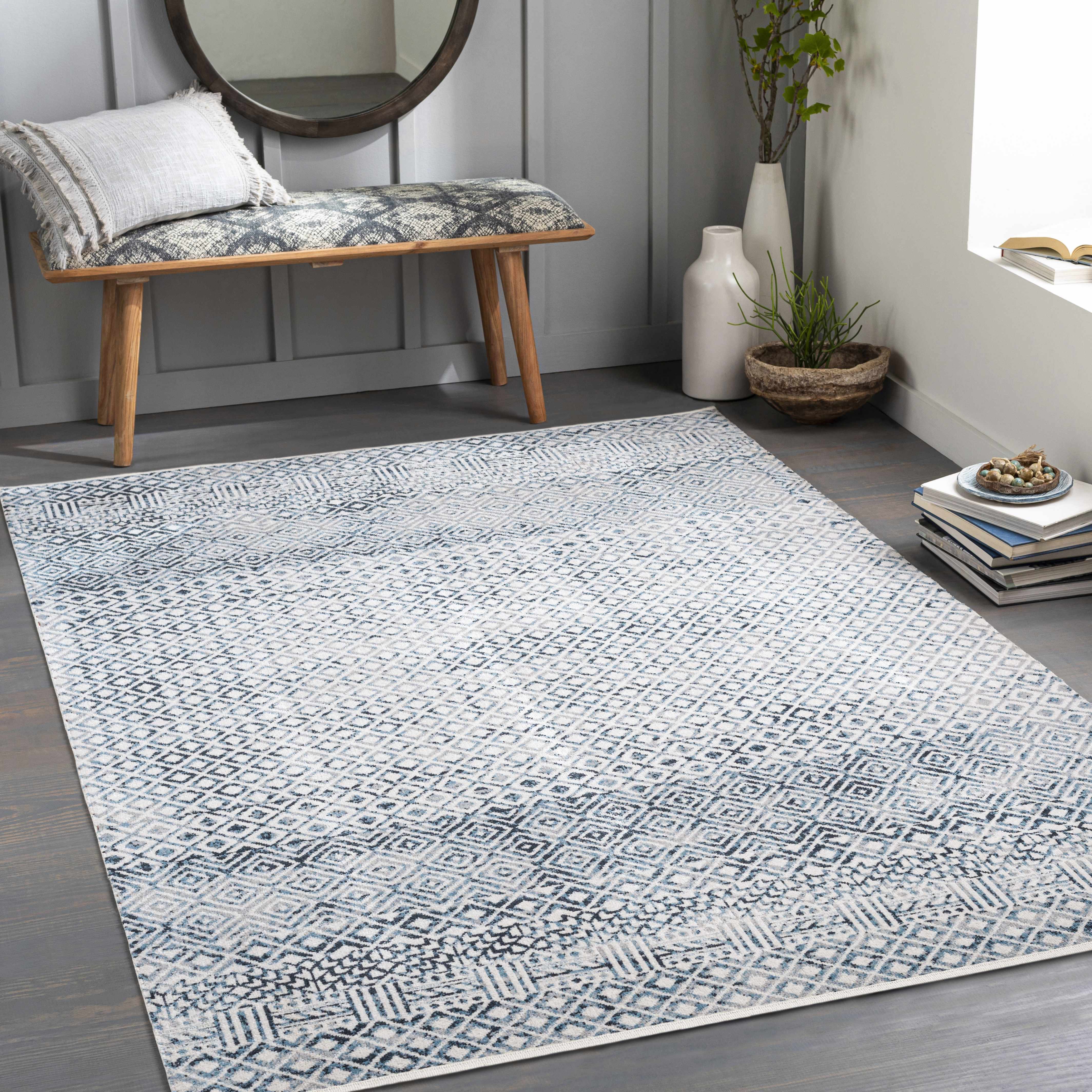 Entryway with blue and gray Askeaton Washable Area Rug, wood bench, round mirror, and gray walls. Roomscene-Rectangle