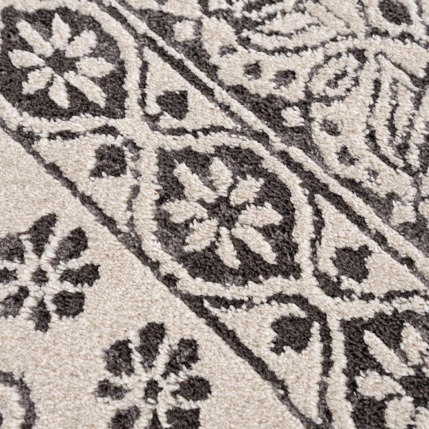 Close-up of the Warroad Area Rug showing a floral and geometric pattern in charcoal, gray, and light beige. Texture