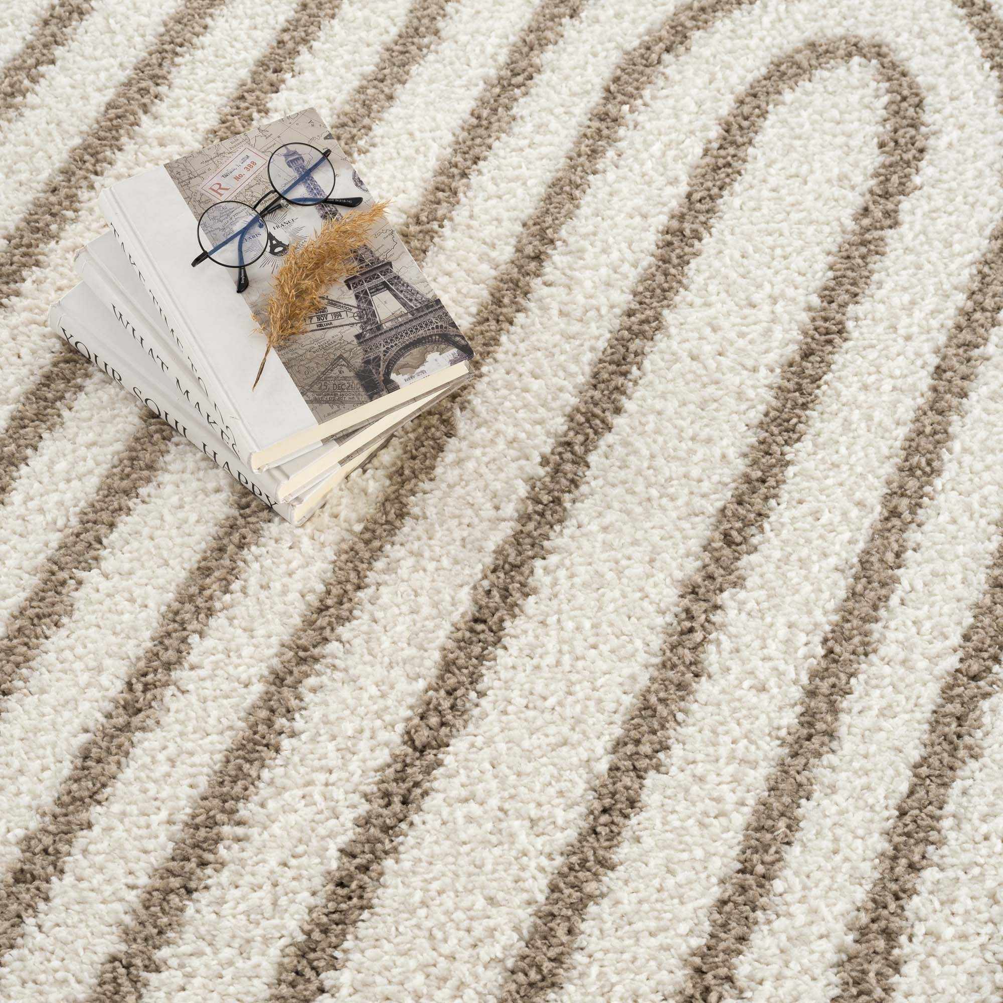 Close-up of the Jola Beige Area Rug featuring a geometric pattern in beige and camel tones. Soft, textured shag pile. Styleshot