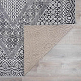 Close-up of the Consuelo Washable Area Rug showing its black, gray, and light gray oriental-inspired pattern and backing. Fold