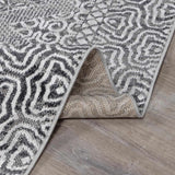 Close-up of the Consuelo Washable Area Rug, showcasing its black, gray, and light gray oriental pattern and machine-woven texture. Fold
