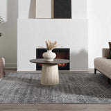 Living room scene with a gray patterned Consuelo Washable Area Rug, round coffee table, fireplace, and neutral sofa. Roomscene-Rectangle