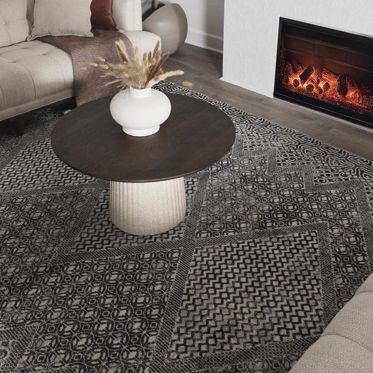 Living room scene with black and gray Consuelo Washable Area Rug under a round coffee table near a fireplace. Roomscene-Rectangle