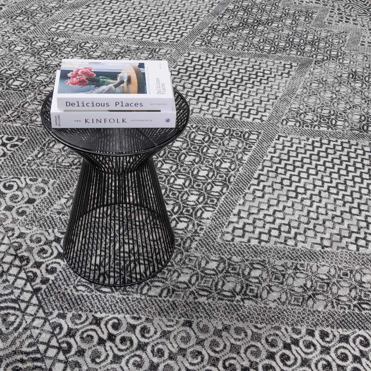 Close-up of the black and gray geometric pattern on the Consuelo Washable Area Rug, with a black accent table. Styleshot