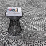 Close-up of the black and gray geometric pattern on the Consuelo Washable Area Rug, with a black accent table. Styleshot
