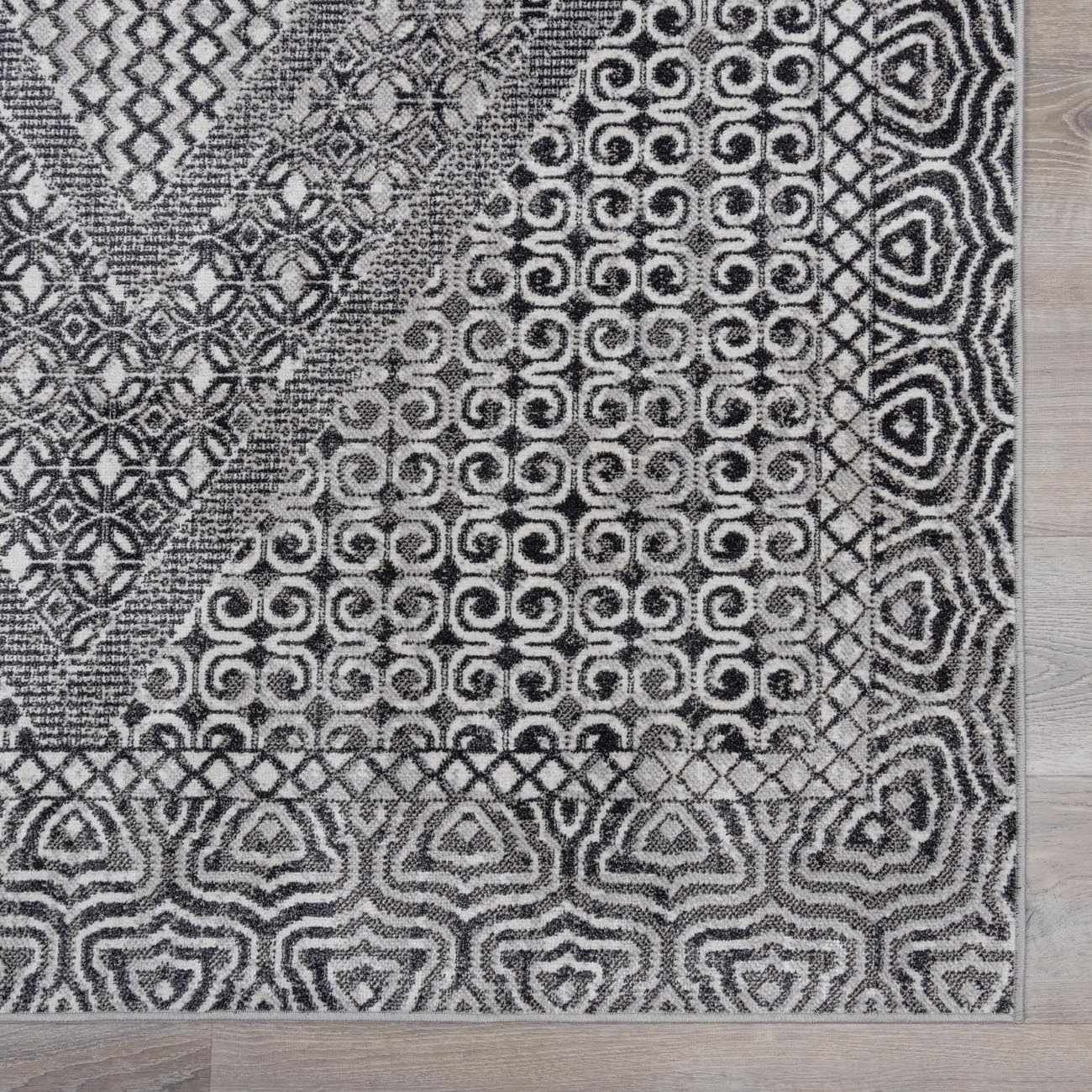 Close-up of the Consuelo Washable Area Rug, showcasing its black, gray, and light gray Oriental-inspired geometric pattern. Swatch