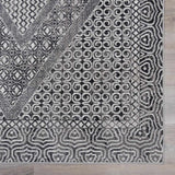 Close-up of the Consuelo Washable Area Rug, showcasing its black, gray, and light gray Oriental-inspired geometric pattern. Swatch