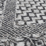 Close-up of the Consuelo Washable Area Rug, showcasing its black and gray geometric pattern and soft, textured weave. Texture