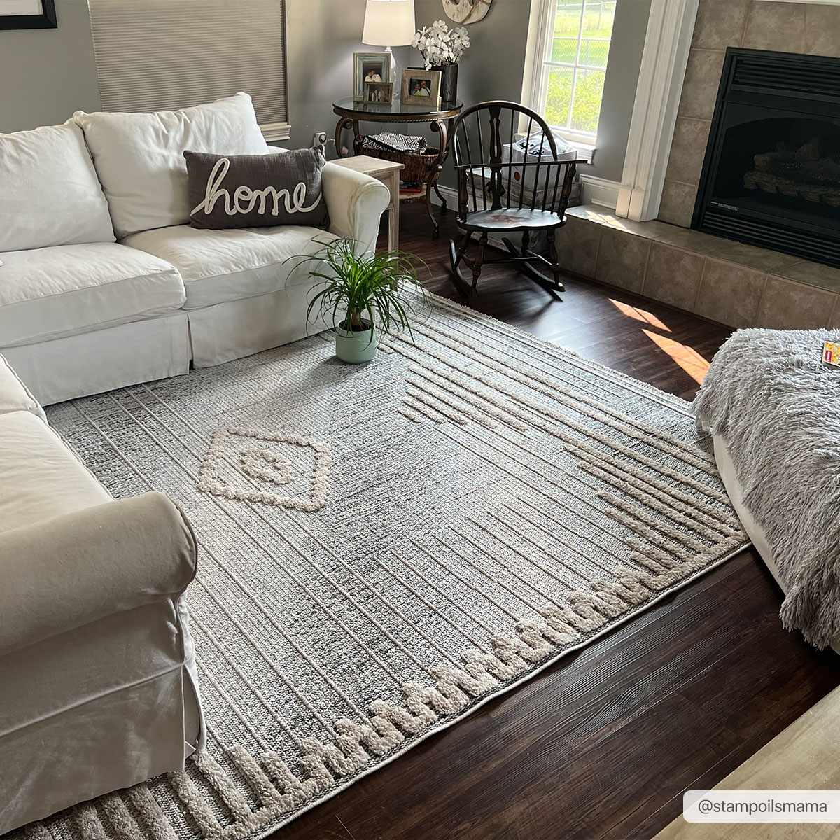Living room scene with a Calituban area rug, white sofa, dark wood floors, and a fireplace. The rug has a geometric, bohemian design. Roomscene-Rectangle