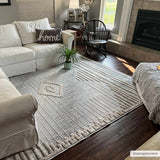 Living room scene with a Calituban area rug, white sofa, dark wood floors, and a fireplace. The rug has a geometric, bohemian design. Roomscene-Rectangle