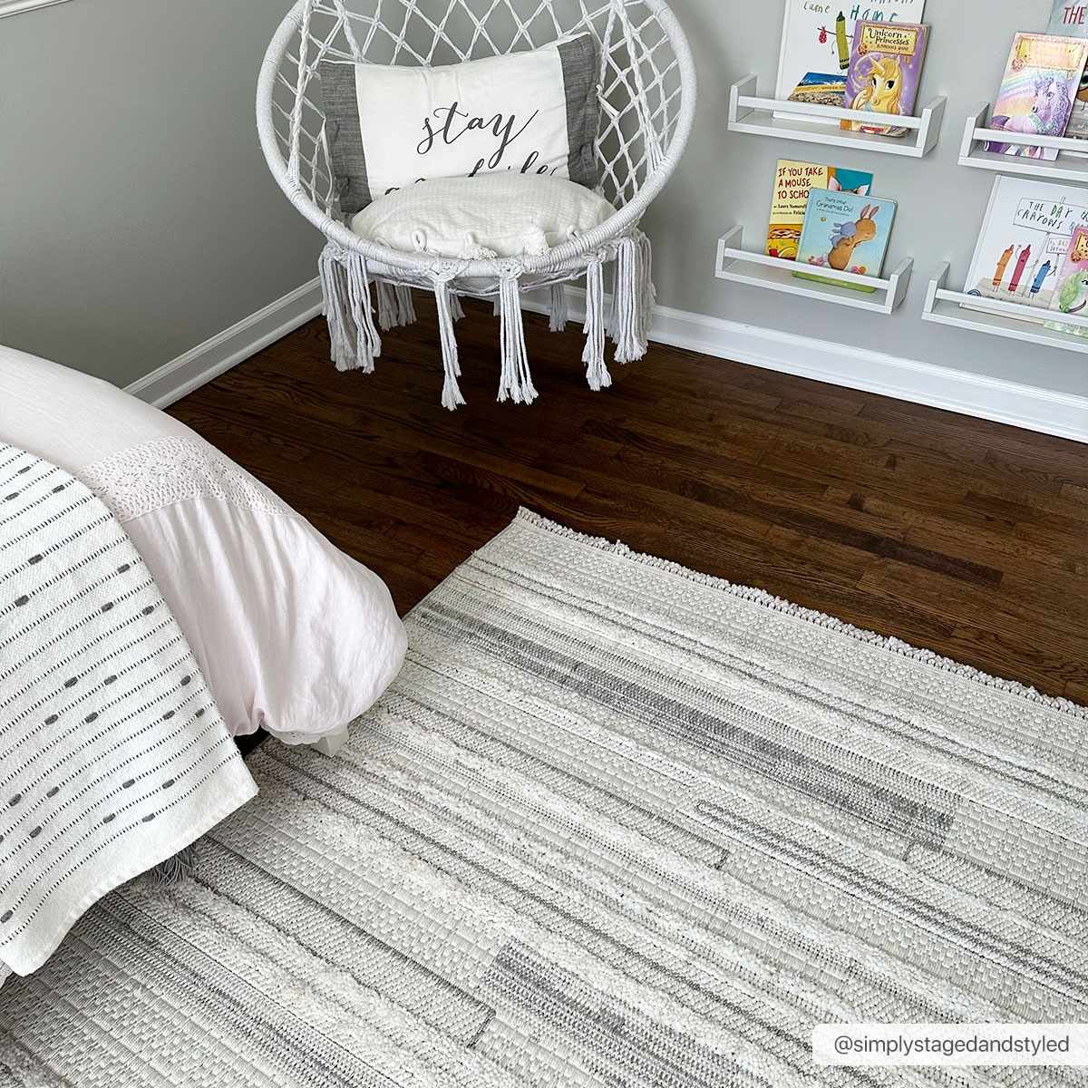 Kids room with cream Dishman Area Rug, white hanging chair, dark wood floors, and book shelves. Roomscene-Rectangle