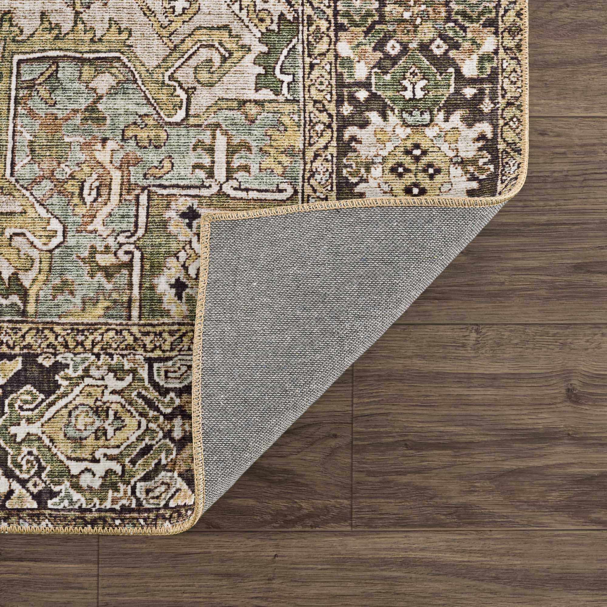 Close-up of the Neyland Sage Green Area Rug showing its oriental pattern, sage, olive, and charcoal colors, and machine-woven texture. Fold