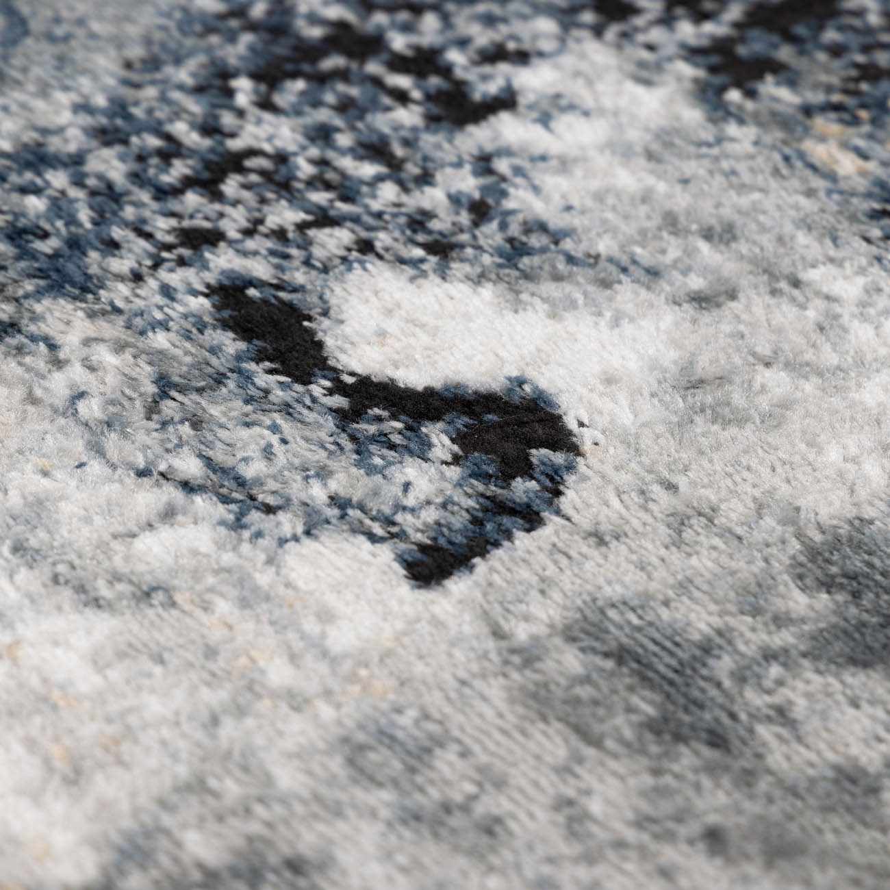 Close-up of Kirkland Dark Blue Marble Rug. Abstract pattern in dark blue, black, and shades of gray. Soft, textured pile. Texture