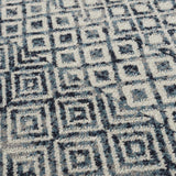 Close-up of the Askeaton Washable Area Rug showing a geometric square pattern in blue, gray, and light gray tones. Texture