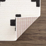 Close-up of the Erath Area Rug showing a black and off-white geometric pattern and the rug's backing. Fold