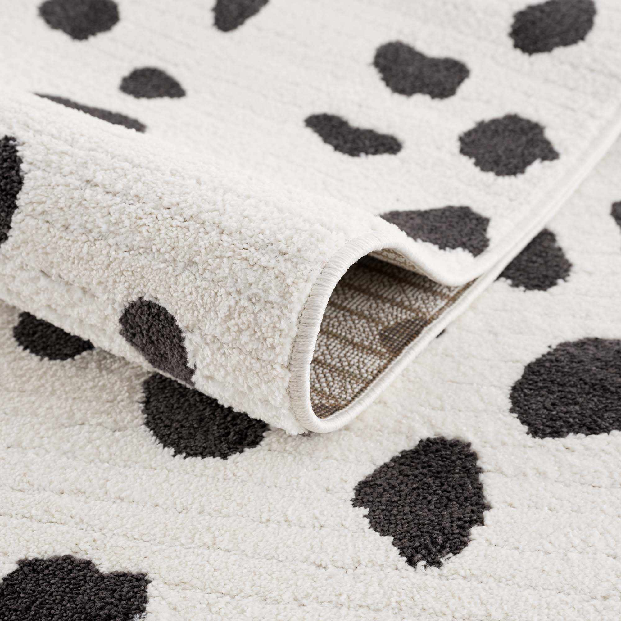 Close-up of the plush Tariffville Dalmatian Rug. Features a black and off-white animal print pattern. Fold