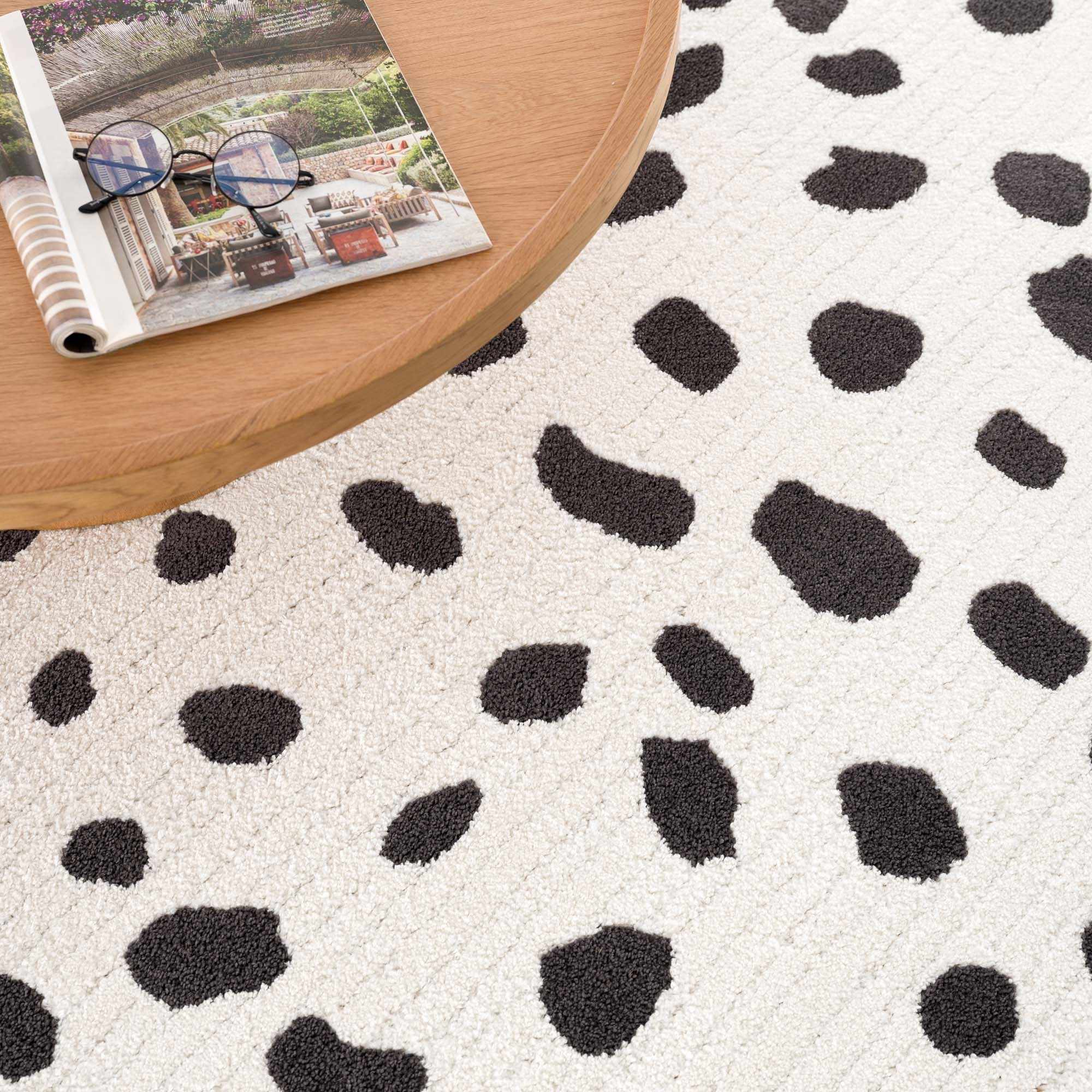 Close-up of the Tariffville Dalmatian Rug, a shag rug with black spots on an off-white background. Styleshot
