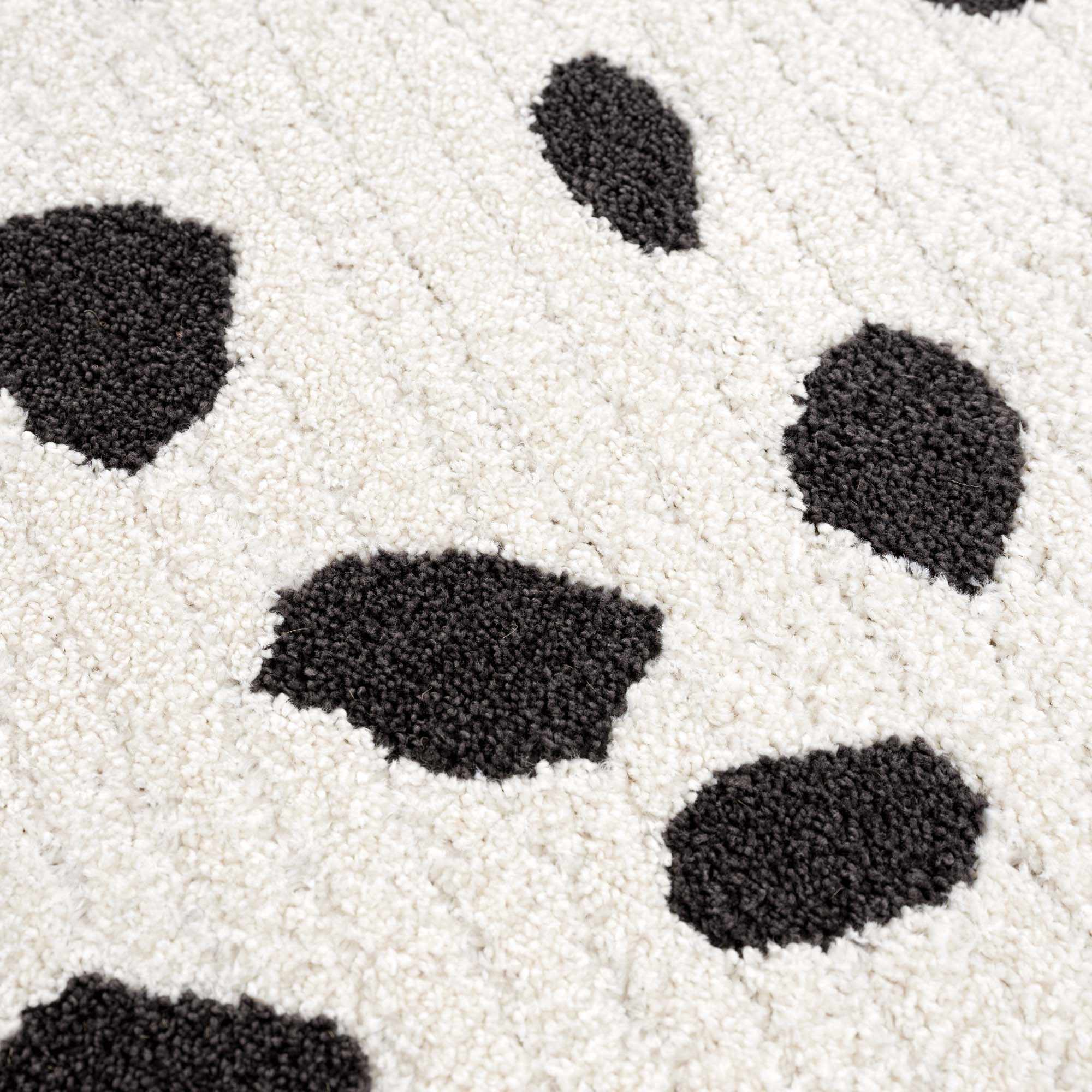 Close-up of the Tariffville Dalmatian Rug. Features a black and off-white animal print shag design. Texture