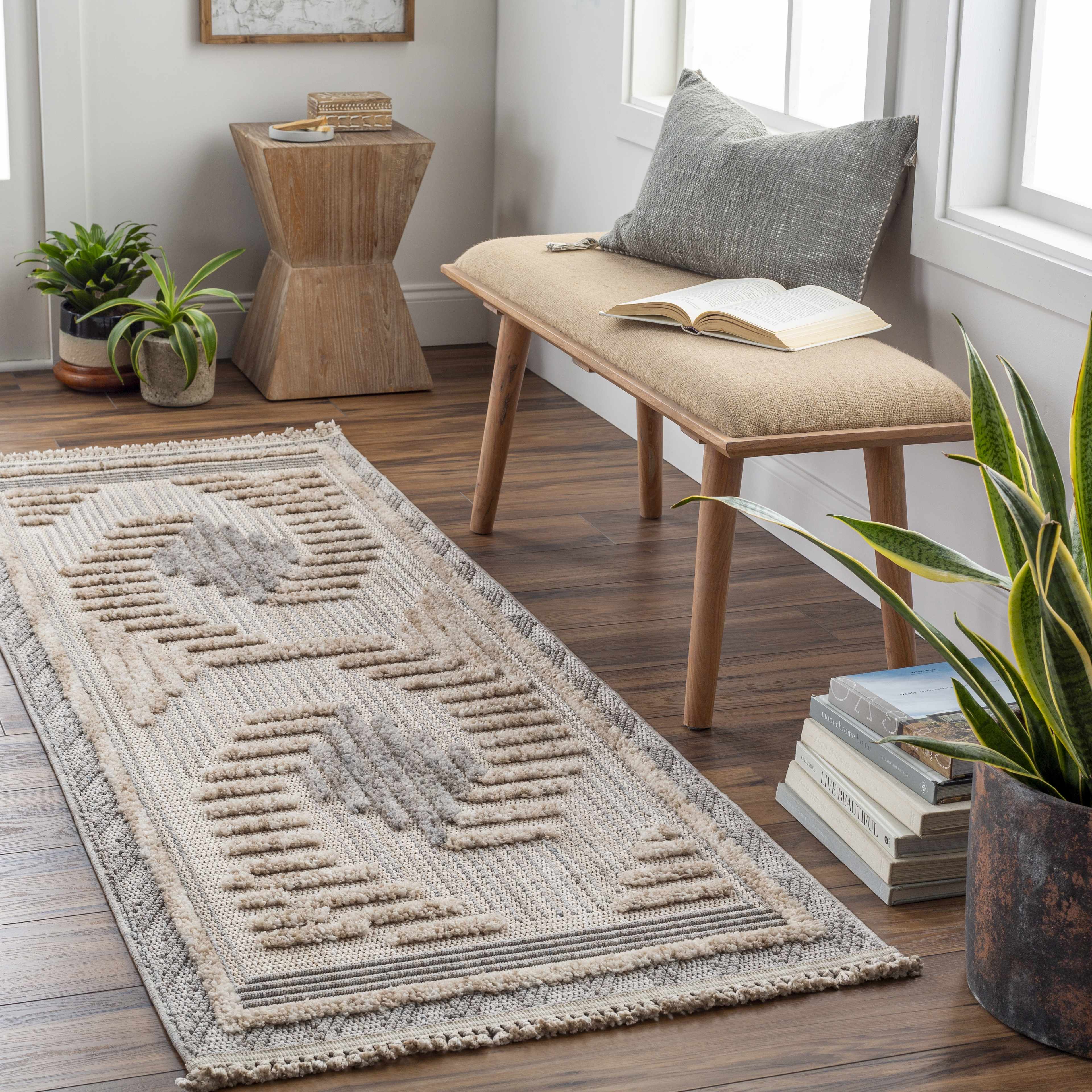 Entryway scene with a Muricay High-Low Rustic Rug in charcoal, cream, and beige, styled with a bench and plants. Roomscene-Runner