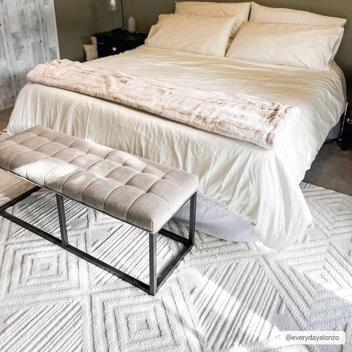 Bedroom scene with a Manyas 3D Bone Area Rug, white bedding, and a gray upholstered bench. Neutral and cozy style. Roomscene-Rectangle