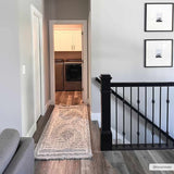 Hallway scene with a cream Muricay High-Low Rustic Rug leading to a laundry room with gray wood floors. Roomscene-Runner