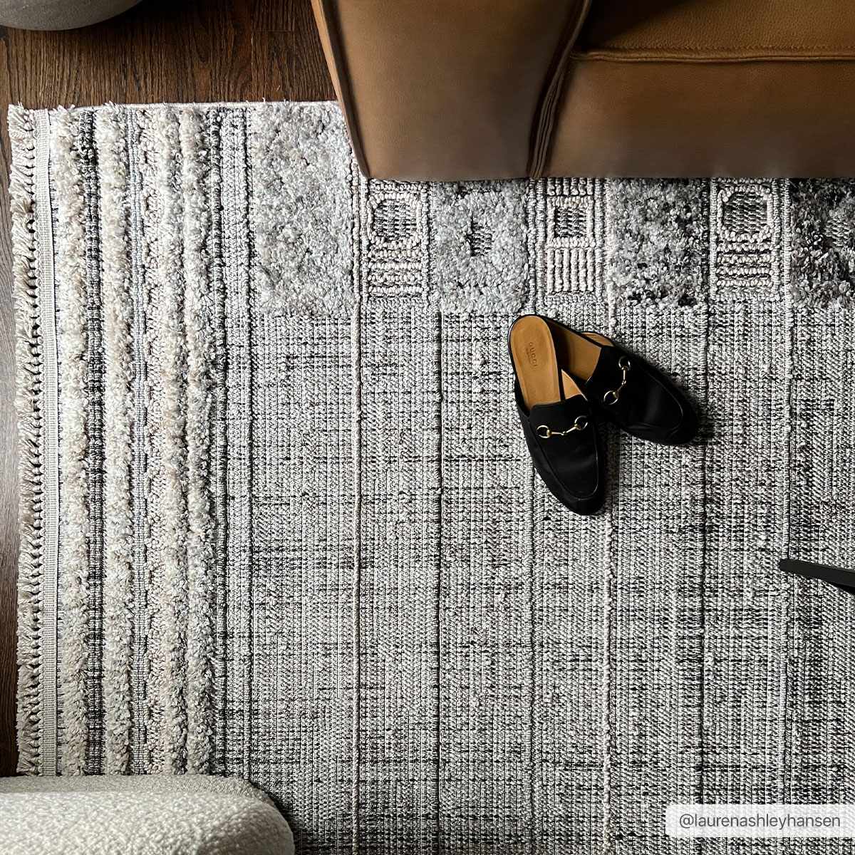 Close-up of the Naivasha Elegant High/Low Area Rug in charcoal and cream, with a textured, geometric design. Styleshot