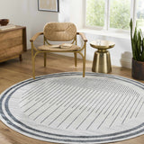 Living room scene with a round Thad Medium Gray Washable Area Rug, woven chair, wood dresser, and gold side table. Roomscene-Round