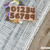 Close-up of the gray and white textured Silanga Area Rug with a fringe border, styled with books and a wooden number puzzle. Roomscene-Rectangle
