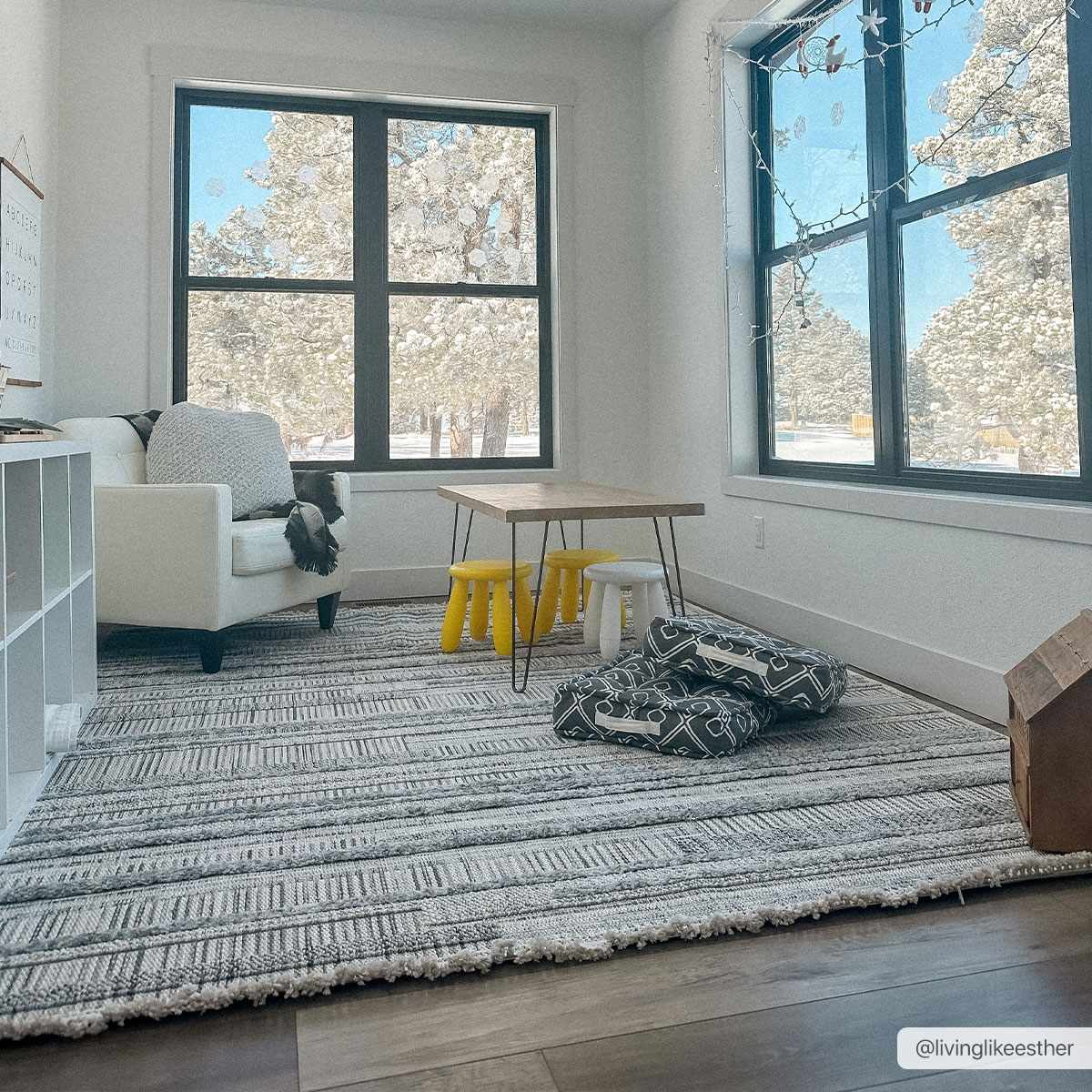 Bright kids room with Silanga area rug, white armchair, small table with yellow stools, and large windows. Roomscene-Rectangle