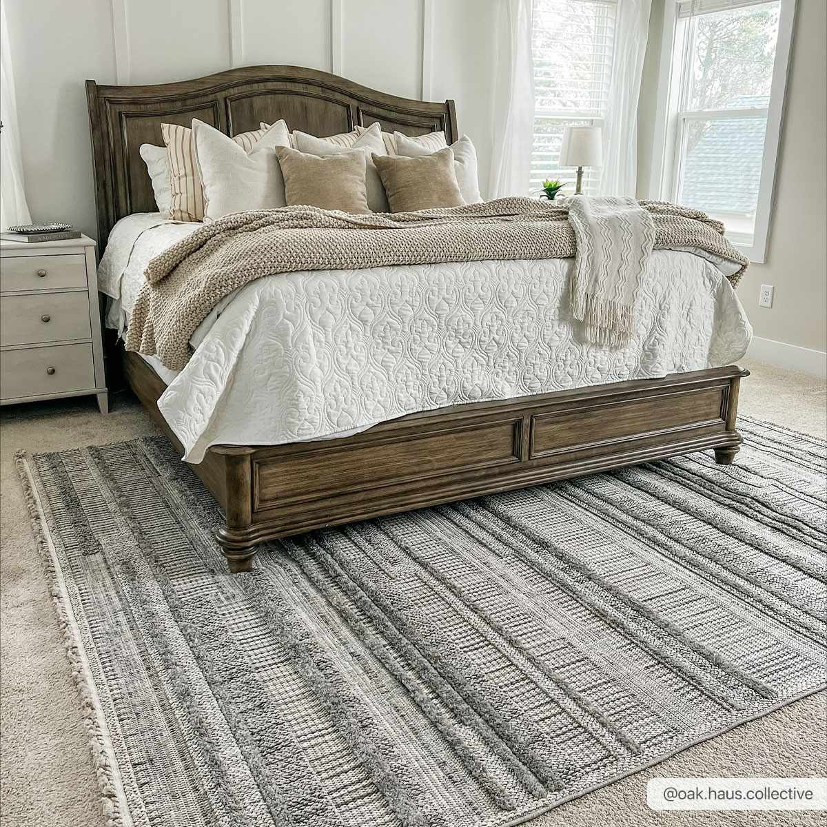 Bedroom scene with a gray and white striped Silanga Area Rug under a wooden bed with neutral bedding. Roomscene-Rectangle