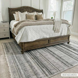 Bedroom scene with a gray and white striped Silanga Area Rug under a wooden bed with neutral bedding. Roomscene-Rectangle