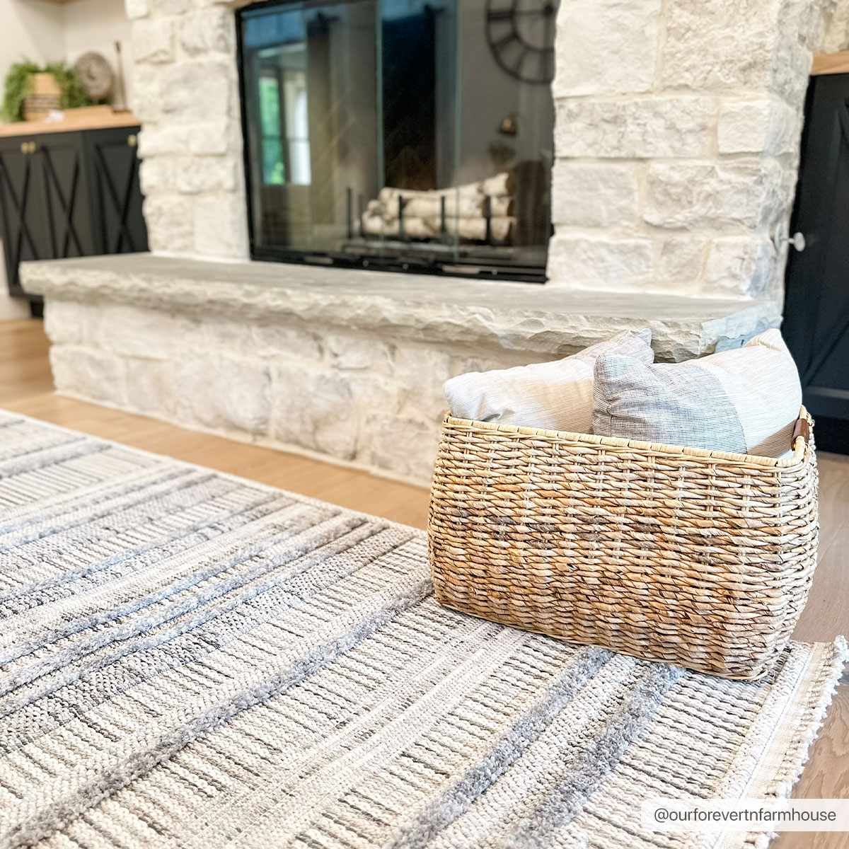 Living room scene with a Silanga area rug in gray tones, styled with a stone fireplace and woven basket. Roomscene-Rectangle