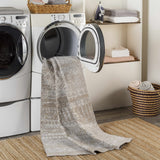 Laundry room scene with Tupsan Washable Area Rug coming out of dryer, jute rug underneath, neutral tones. Washing-Machine