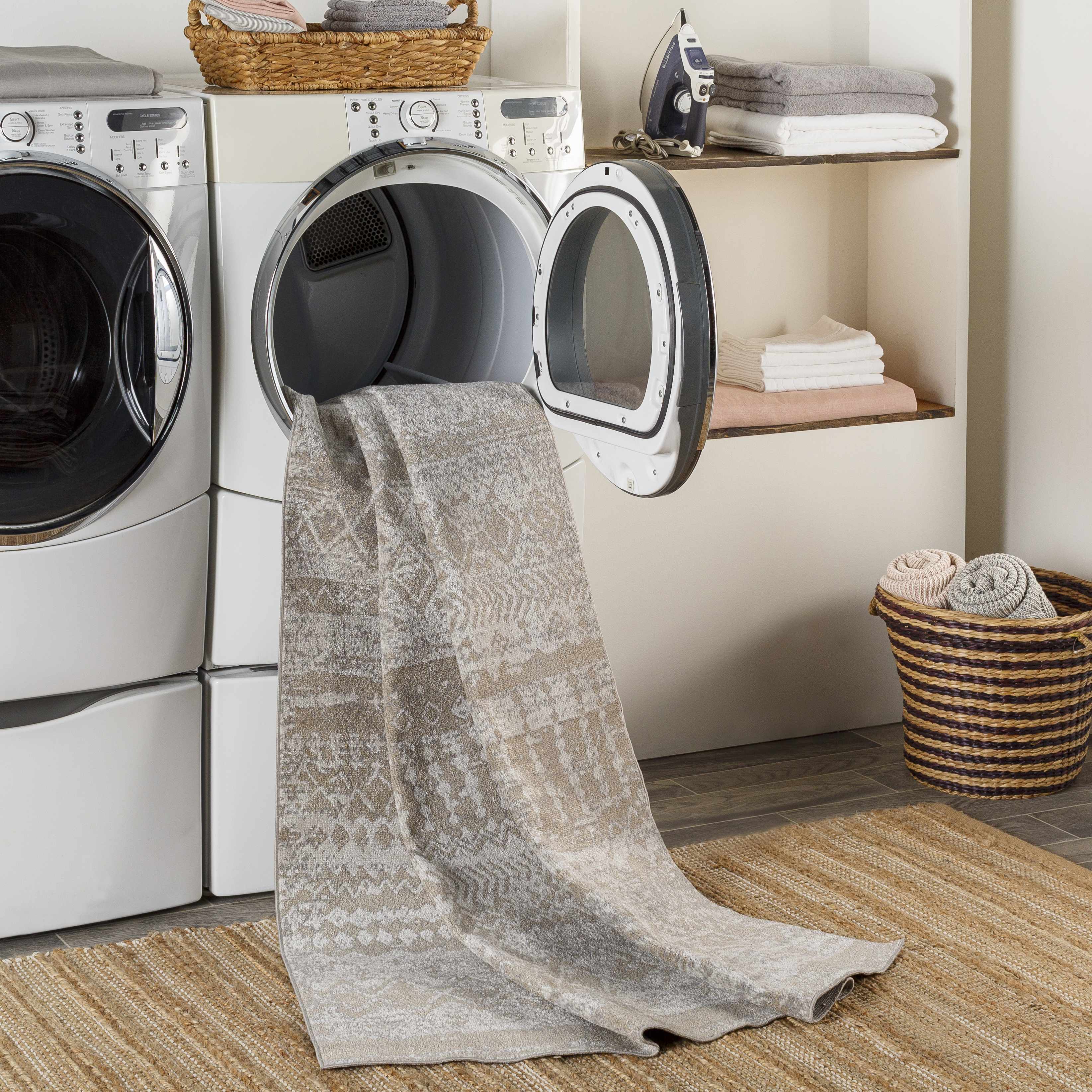 Laundry room scene with Tupsan Washable Area Rug coming out of dryer, jute rug underneath, neutral tones. Washing-Machine