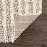 Close-up of the Emmly Shag Area Rug showing its white thatch, gray, and nutmeg colors, plus the rug's backing. Fold