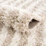 Close-up of the Emmly Shag Area Rug showing its plush, white thatch and light peach fibers, and machine-woven construction. Fold