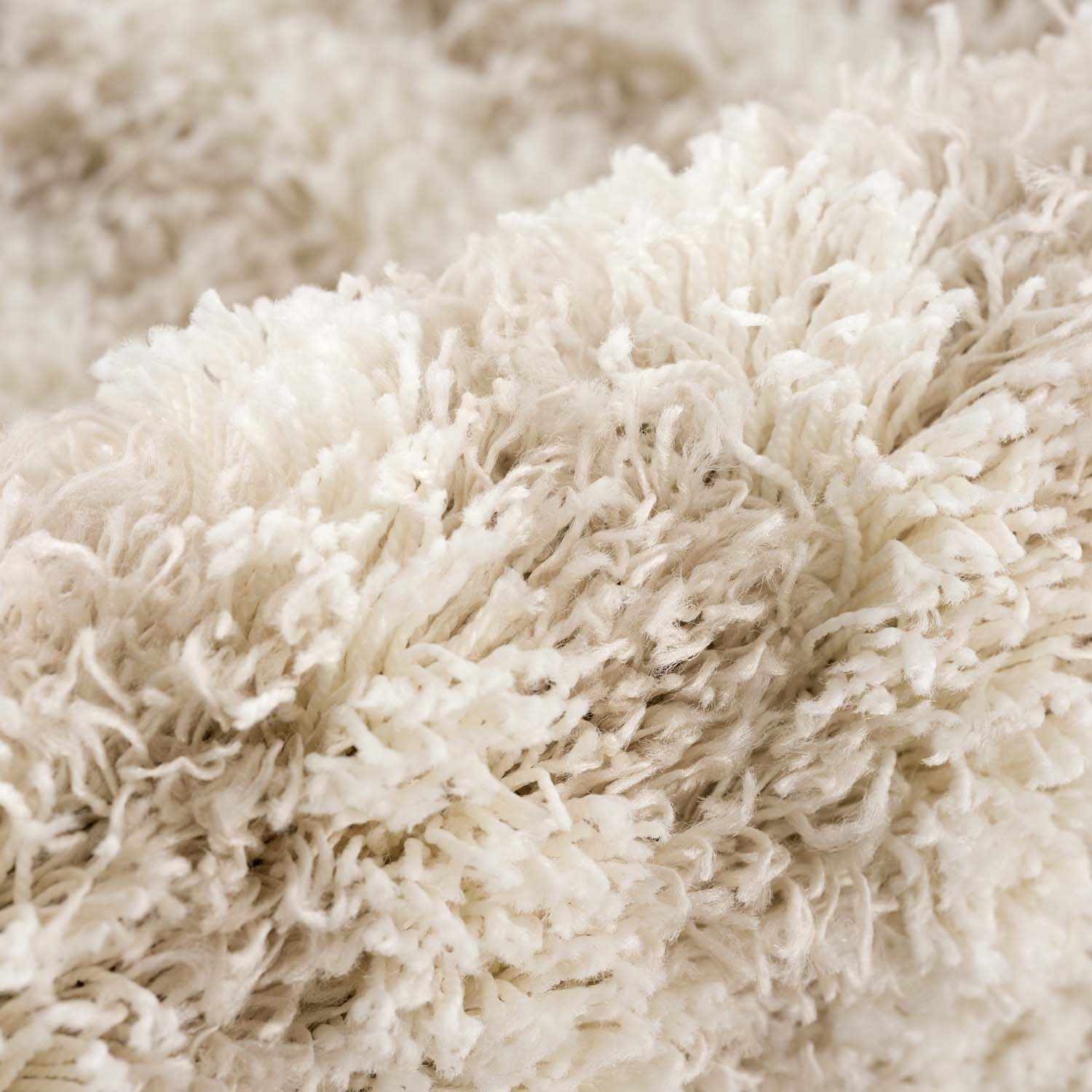 Close-up of the Emmly Shag Area Rug, showing its plush white thatch texture and subtle gray and nutmeg tones. Fold