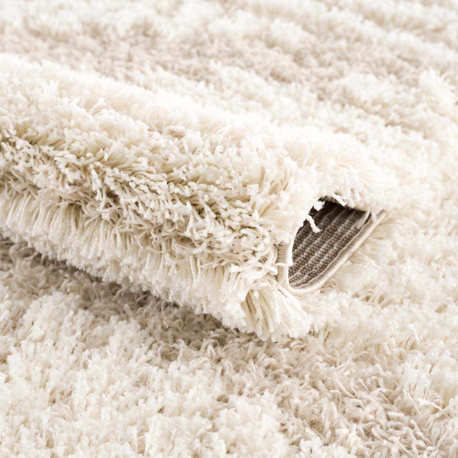 Close-up of the plush Igor Shag Area Rug, showing its soft, shaggy texture in light gray and cream tones. Fold