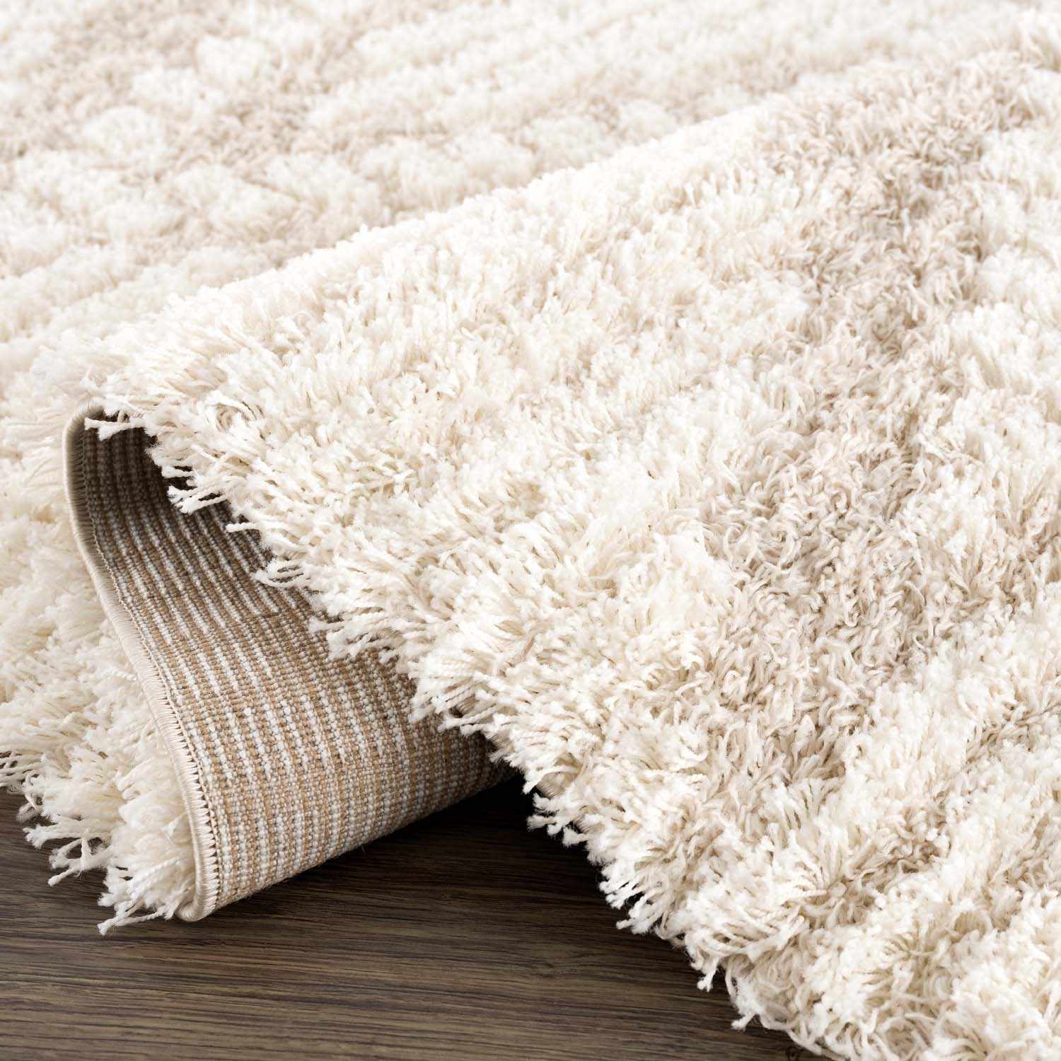 Close-up of the Igor Shag Area Rug, showing its plush texture, geometric pattern, and gray, light peach, mocha, and nutmeg colors. Fold