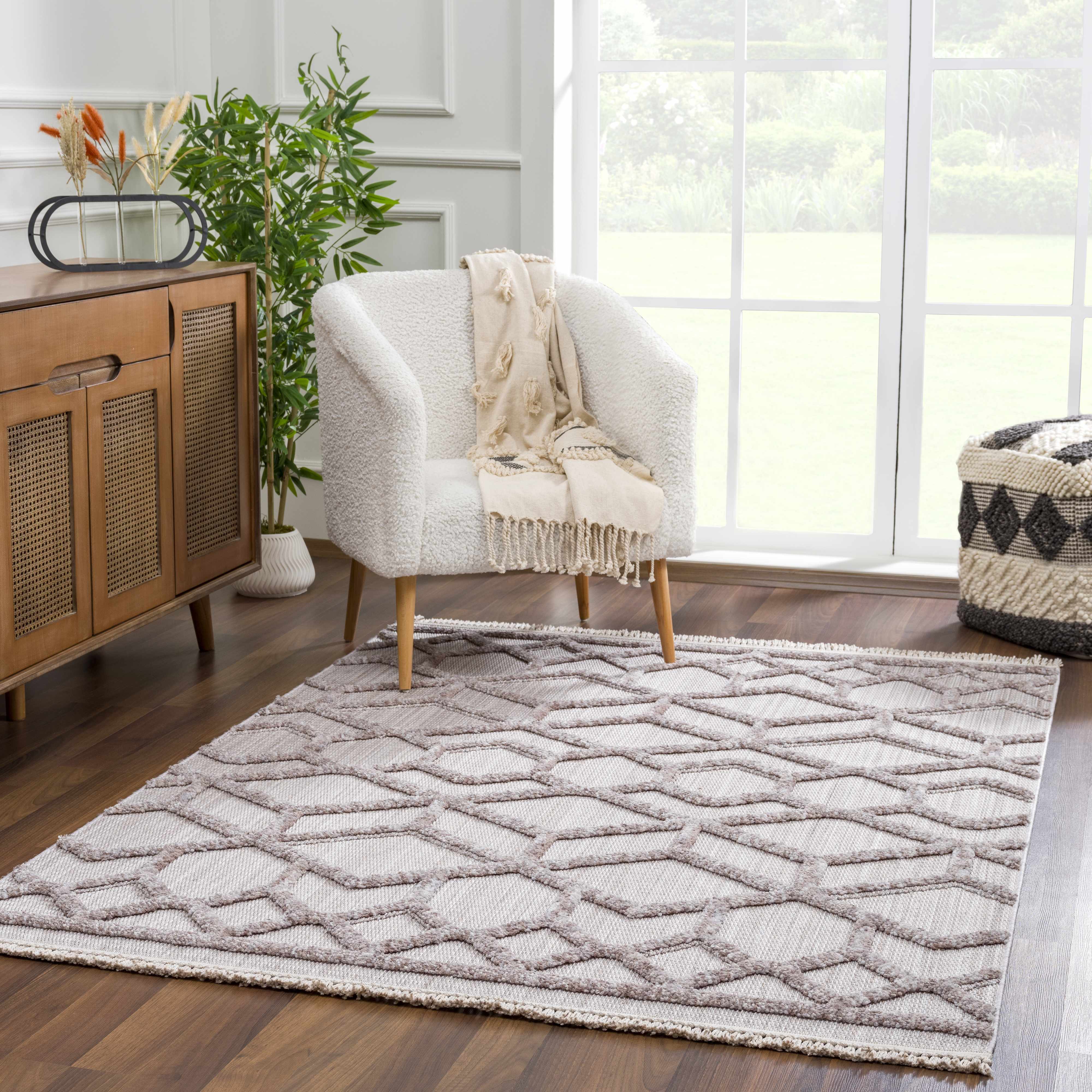 Living room scene with a cream Borbon Area Rug, white chair, wood cabinet, and large window. Roomscene-Rectangle