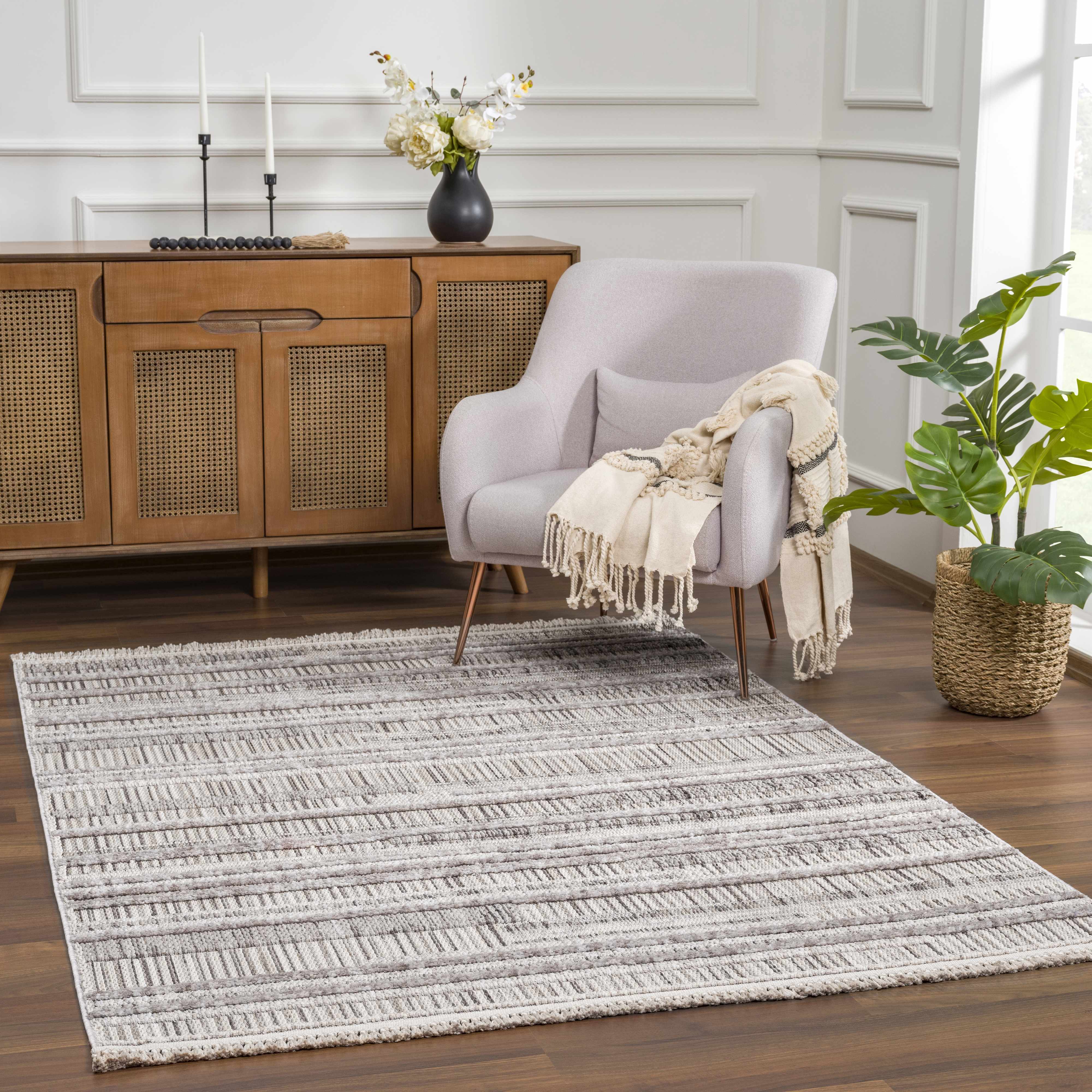Living room scene with a Silanga Area Rug, light gray chair, and wooden cabinet. Roomscene-Rectangle