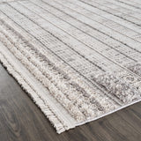 Close-up of the Naivasha Elegant High/Low Area Rug. Cream and charcoal rug with a textured, striped pattern and fringe detail. Corner