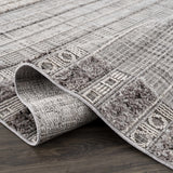 Close-up of the Naivasha Elegant High/Low Area Rug showing its charcoal, cream, and gray textured pattern. Fold