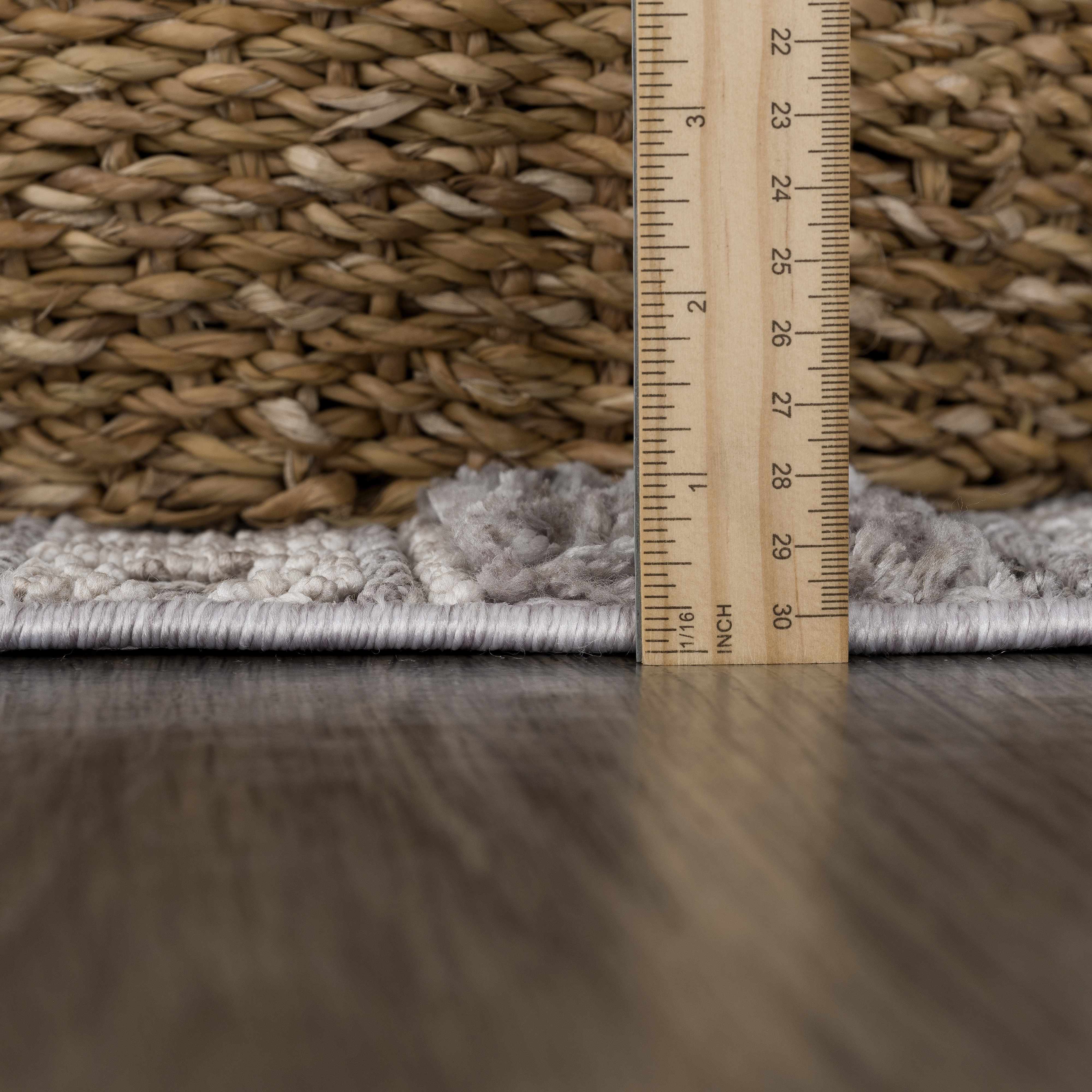 Close-up of the Naivasha rug pile height in light gray, cream, and charcoal with a ruler and basket. Pile