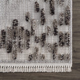Close-up of the Cabarroguis Area Rug. Cream rug with charcoal geometric pattern and fringe detail. Swatch