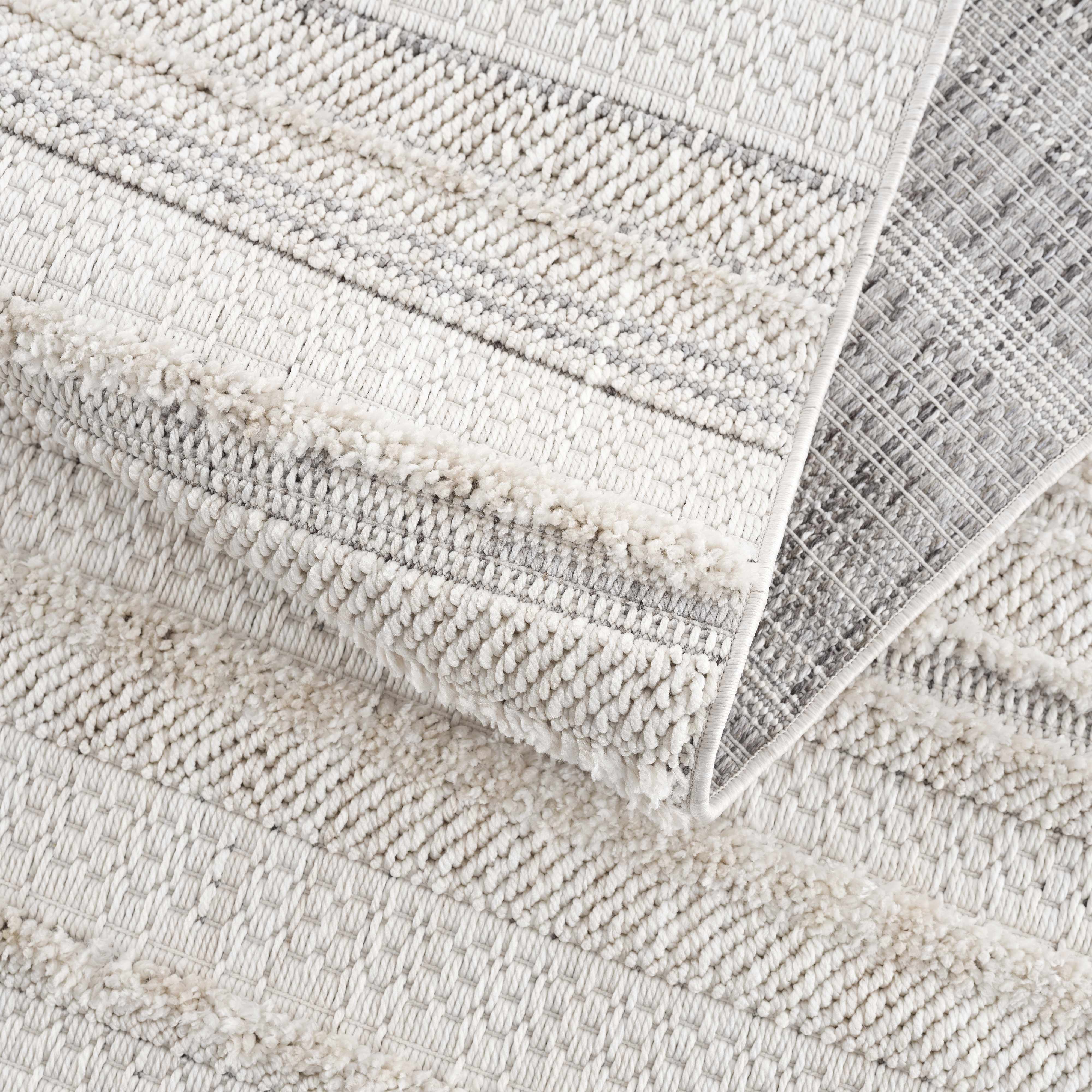 Close-up of the cream and light gray Dishman Area Rug showing geometric stripes and textured, machine-woven construction. Fold
