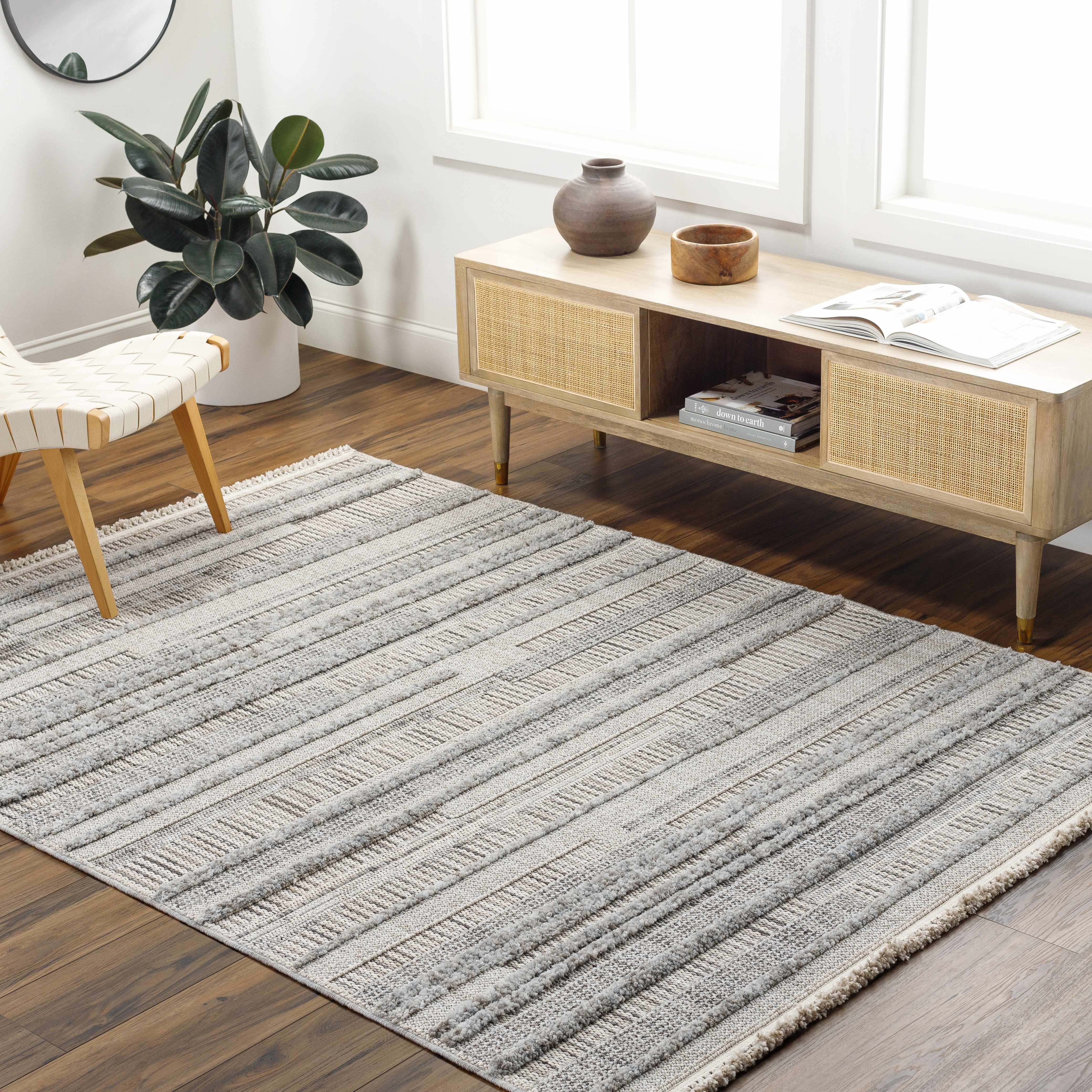 Living room scene with light wood floors, Silanga Area Rug, woven chair, and mid-century modern console table. Roomscene-Rectangle